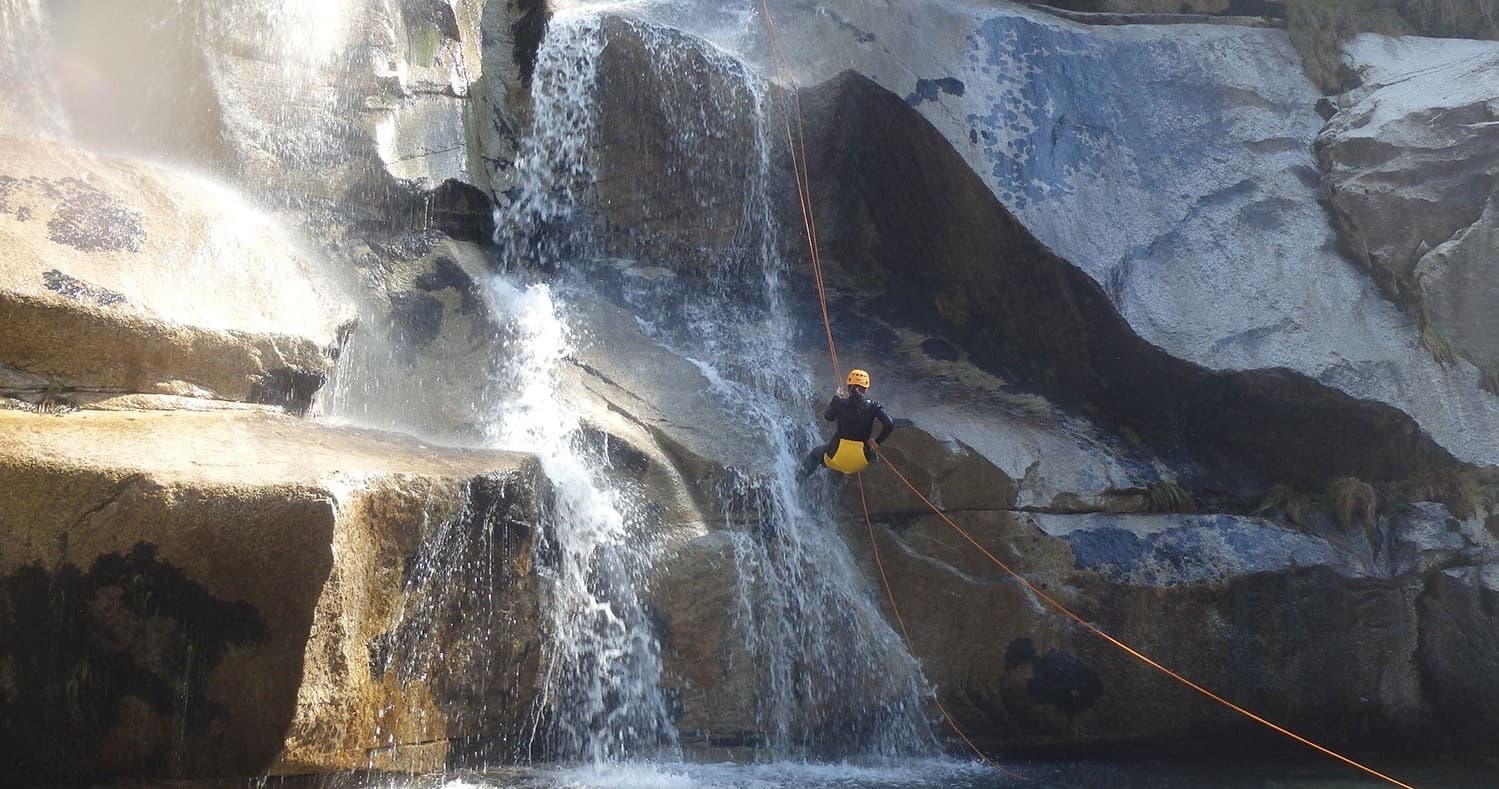 Canyoneer rappelling down waterfall in narrow slot canyon