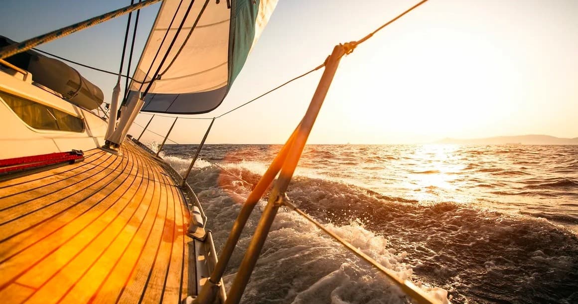 Close-up sailboat deck cutting through waves at sunset