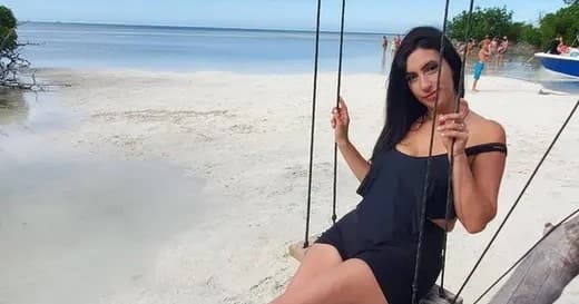 Woman on beach swing posing on white sand shoreline