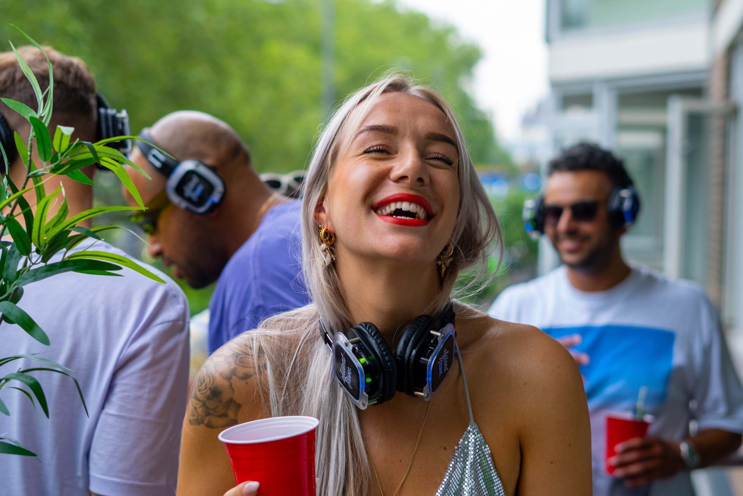 Woman at silent disco on outdoor porch laughing with headphones