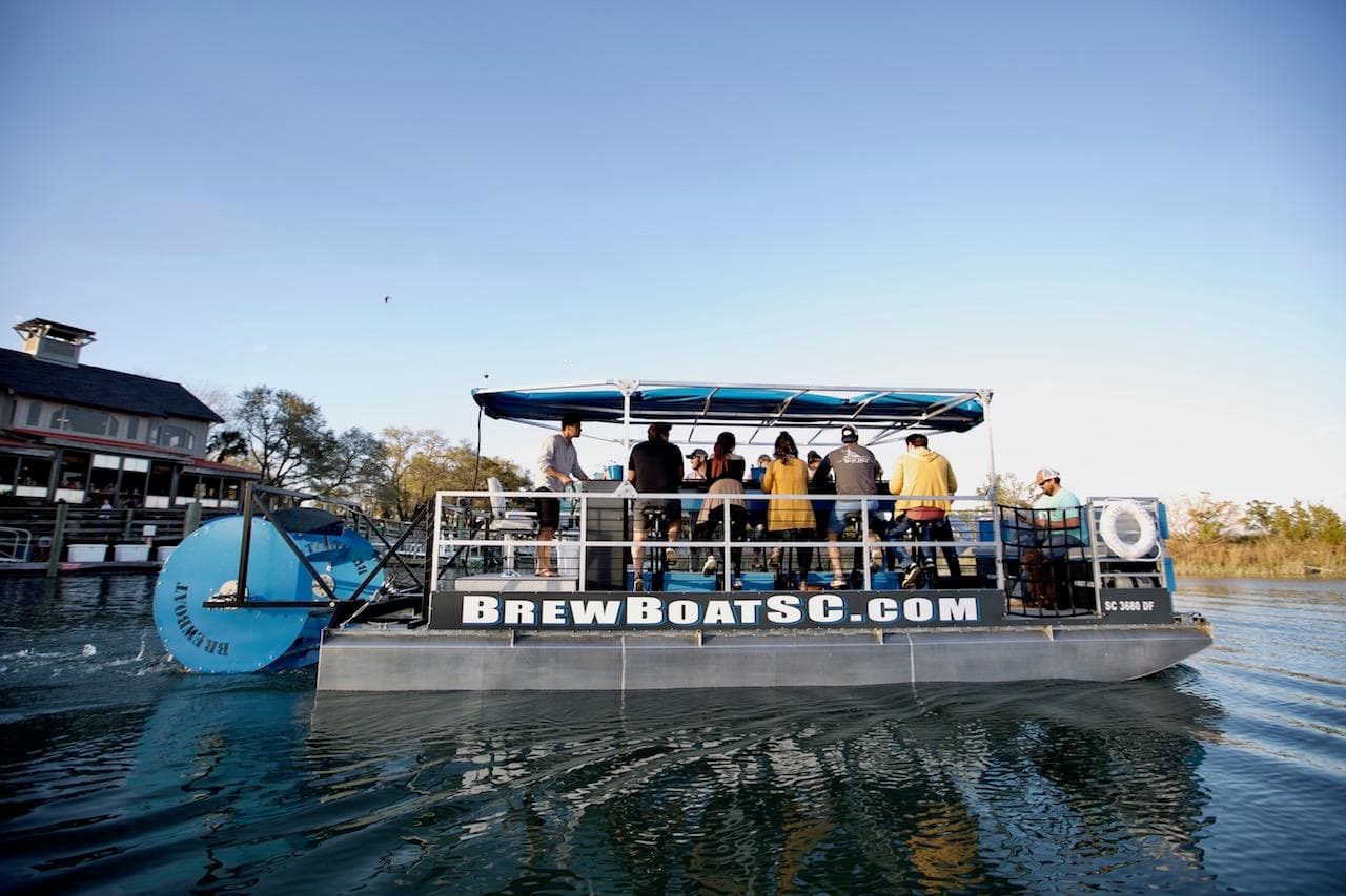 BrewBoat pontoon cruising marsh waterways with passengers onboard