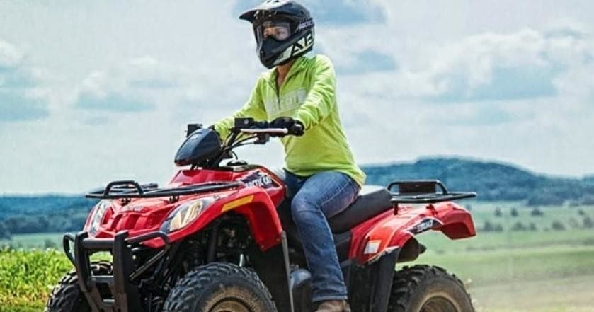 Rider on red ATV enjoying off-road coastal plain ride with horizon