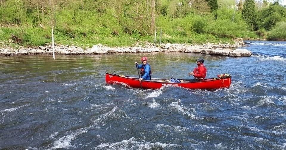 Two-person canoe navigating whitewater rapids in river