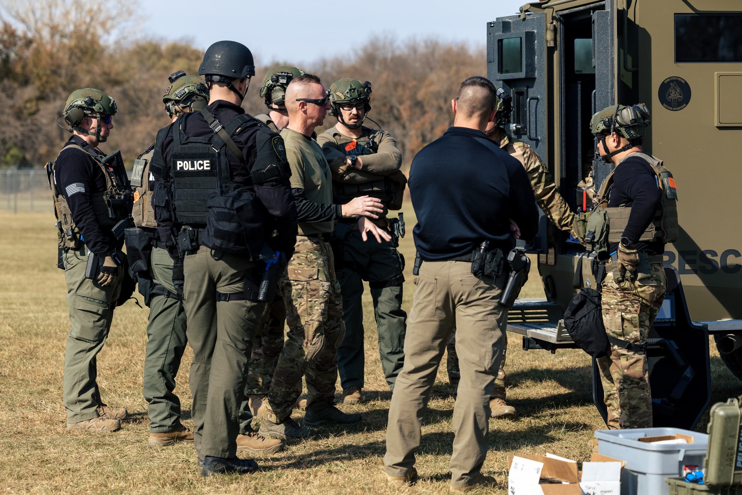 SWAT team briefing on grassy training field outdoors