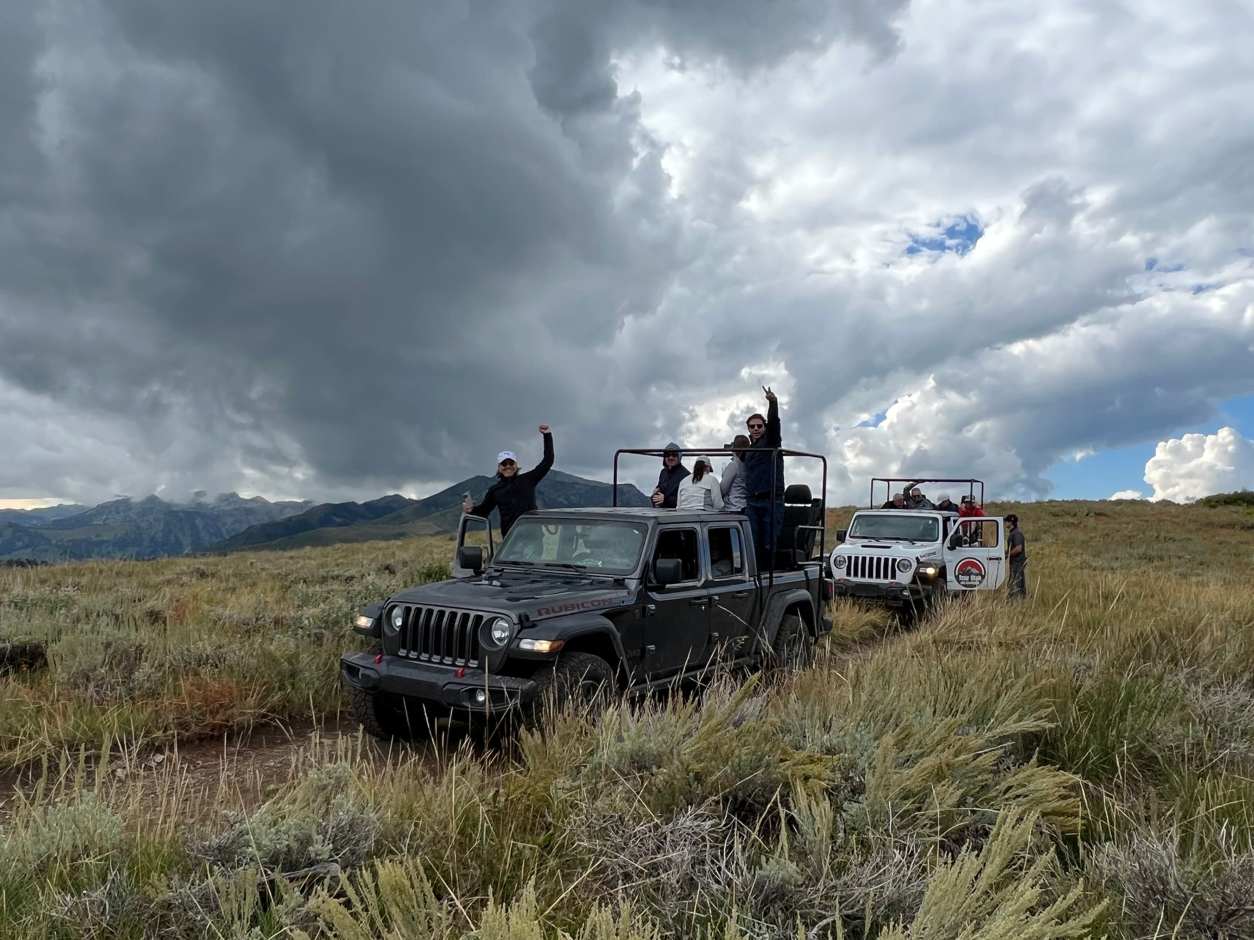 Off-road Jeep convoy in Utah high desert sagebrush, riders waving