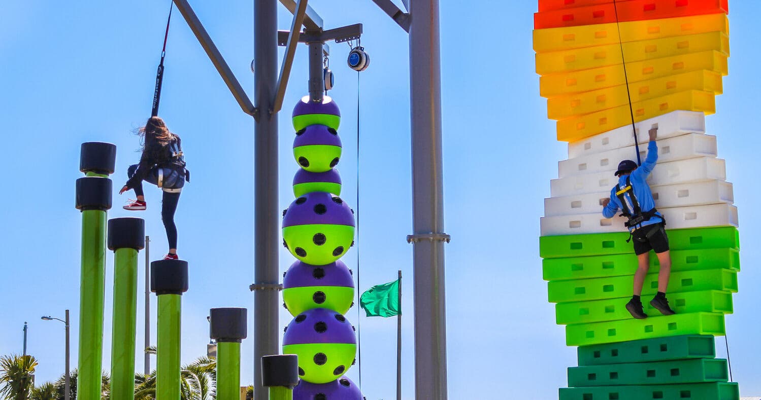 Colorful vertical climbing towers with participants ascending