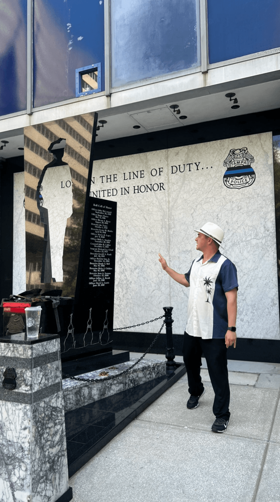 Memorial wall with visitor pointing at names, urban historical walk