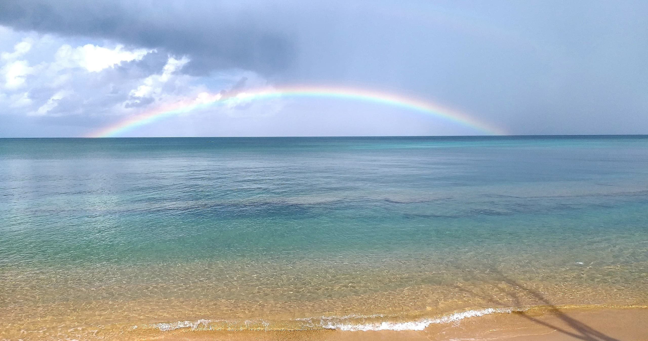 Calm tropical beach with rainbow and snorkeling access