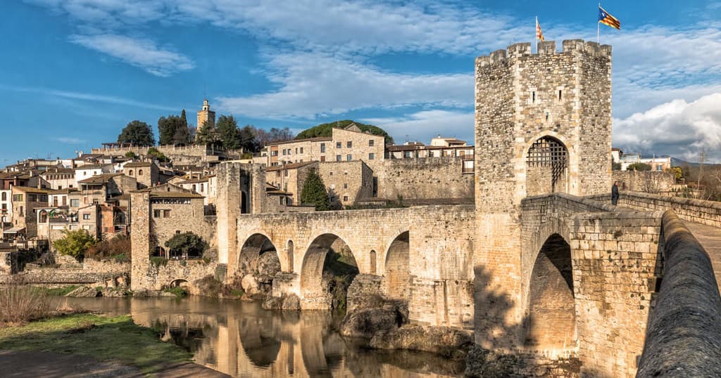Medieval arched bridge reflected in river near Catalonia town