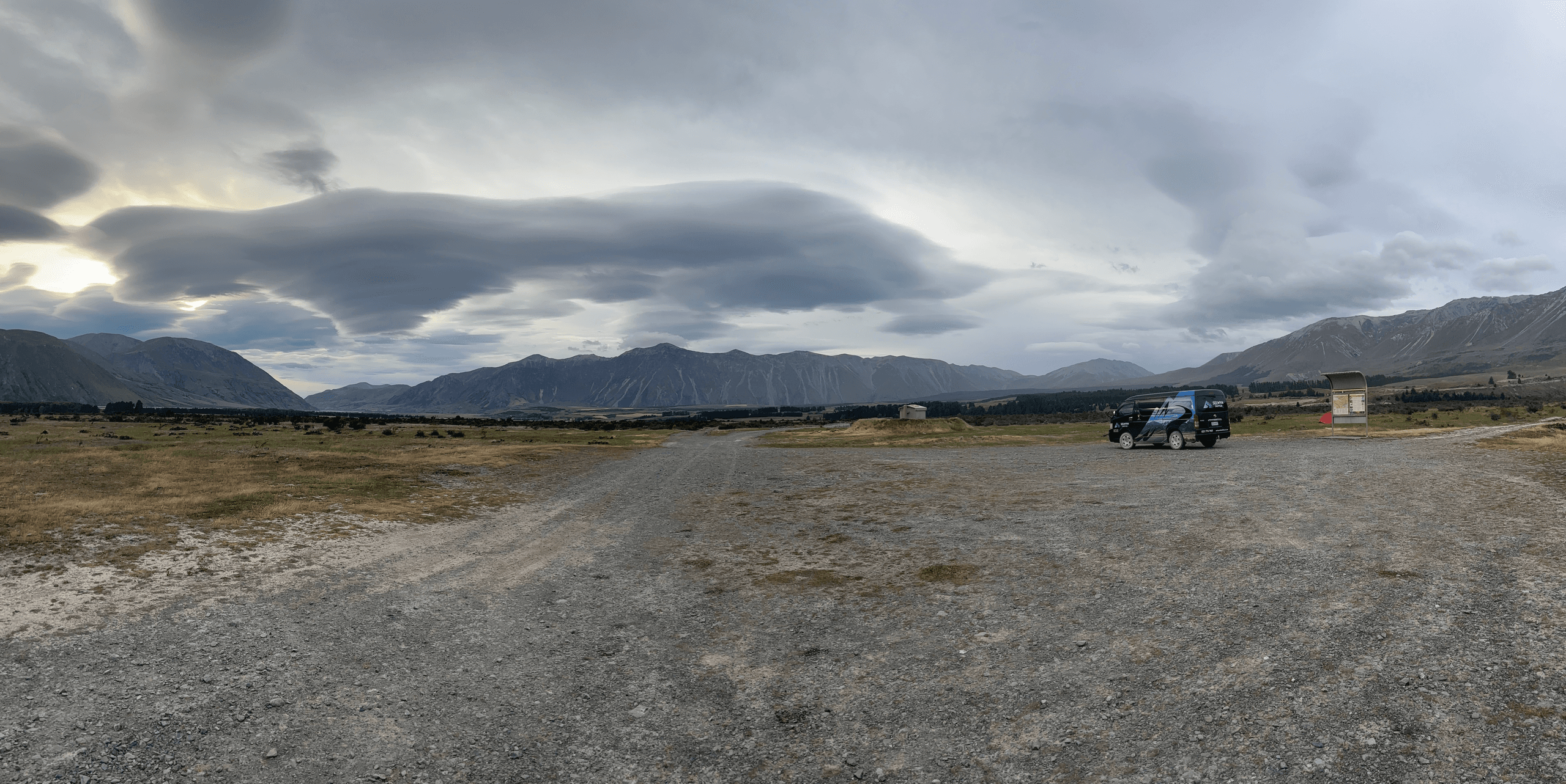 Wide gravel plain under dramatic clouds for backcountry drive
