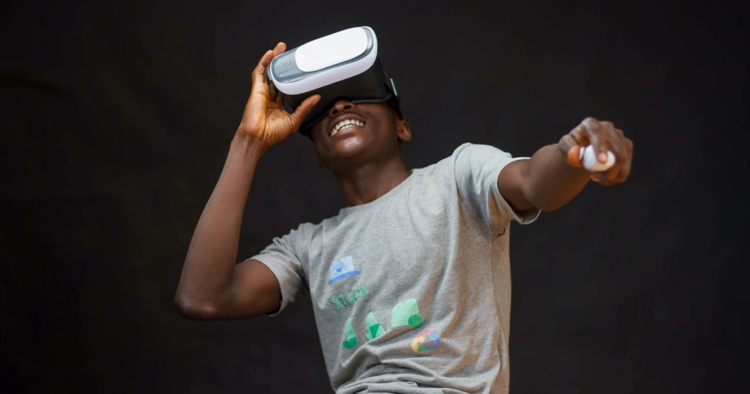 Teen enjoying VR headset pointing and reacting against dark studio