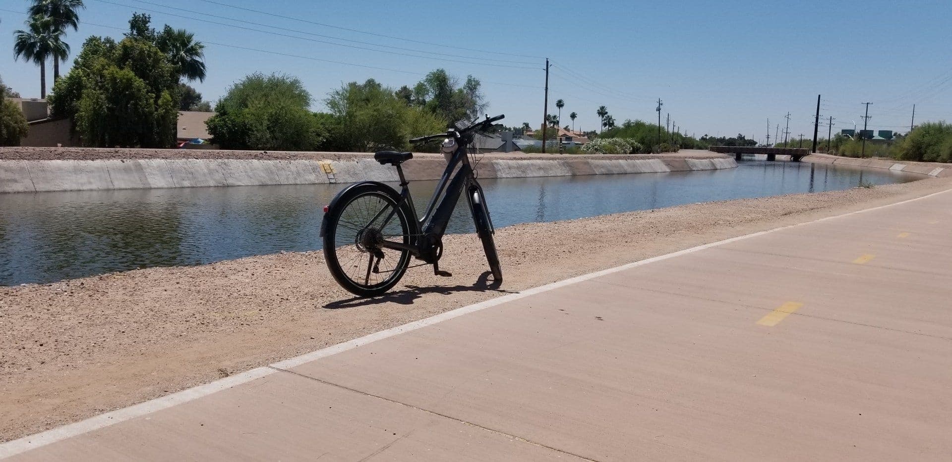 E-bike by canal on paved multiuse trail, urban riverside ride