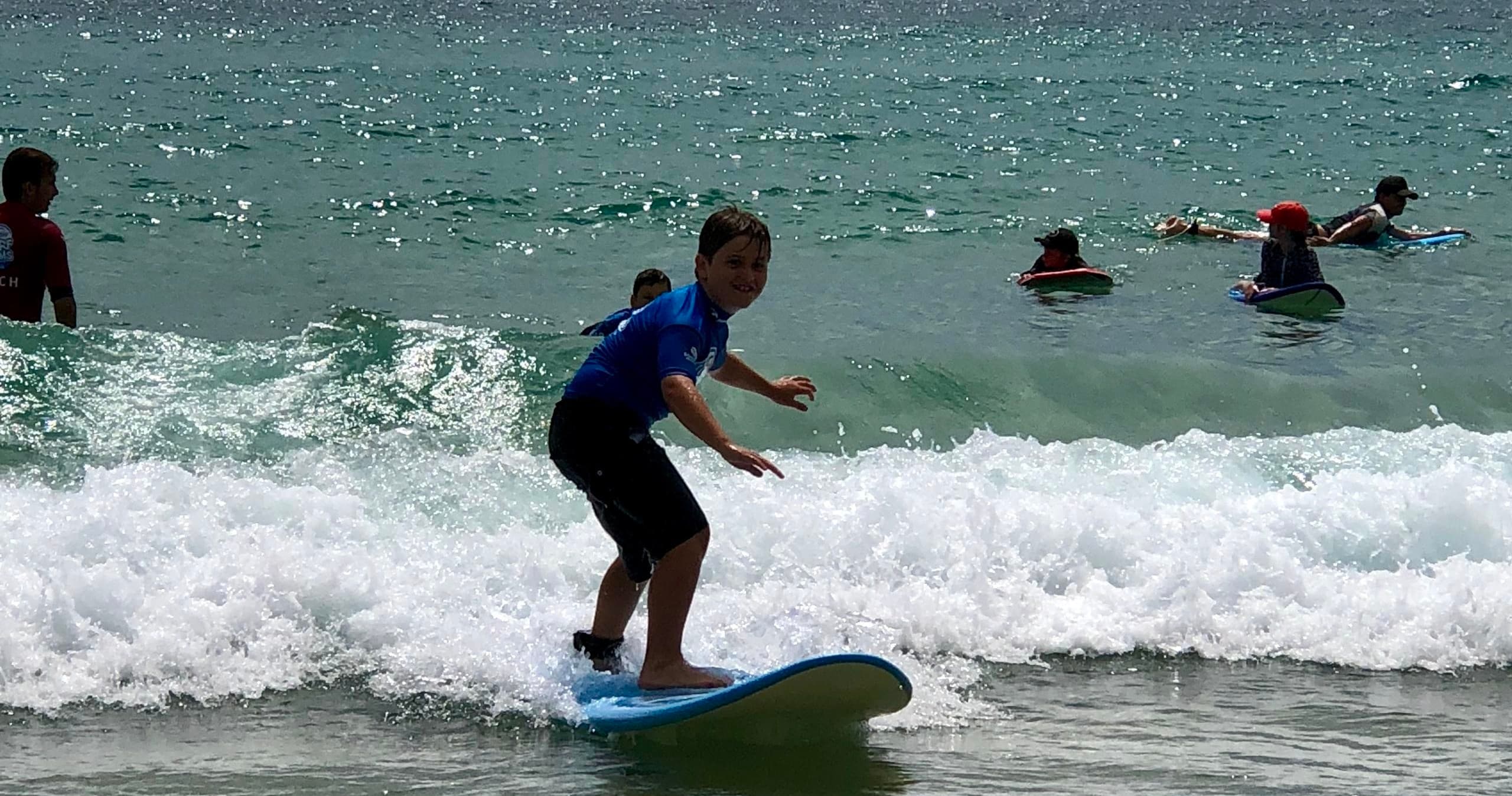 Young surfer riding small wave toward shore during lesson session