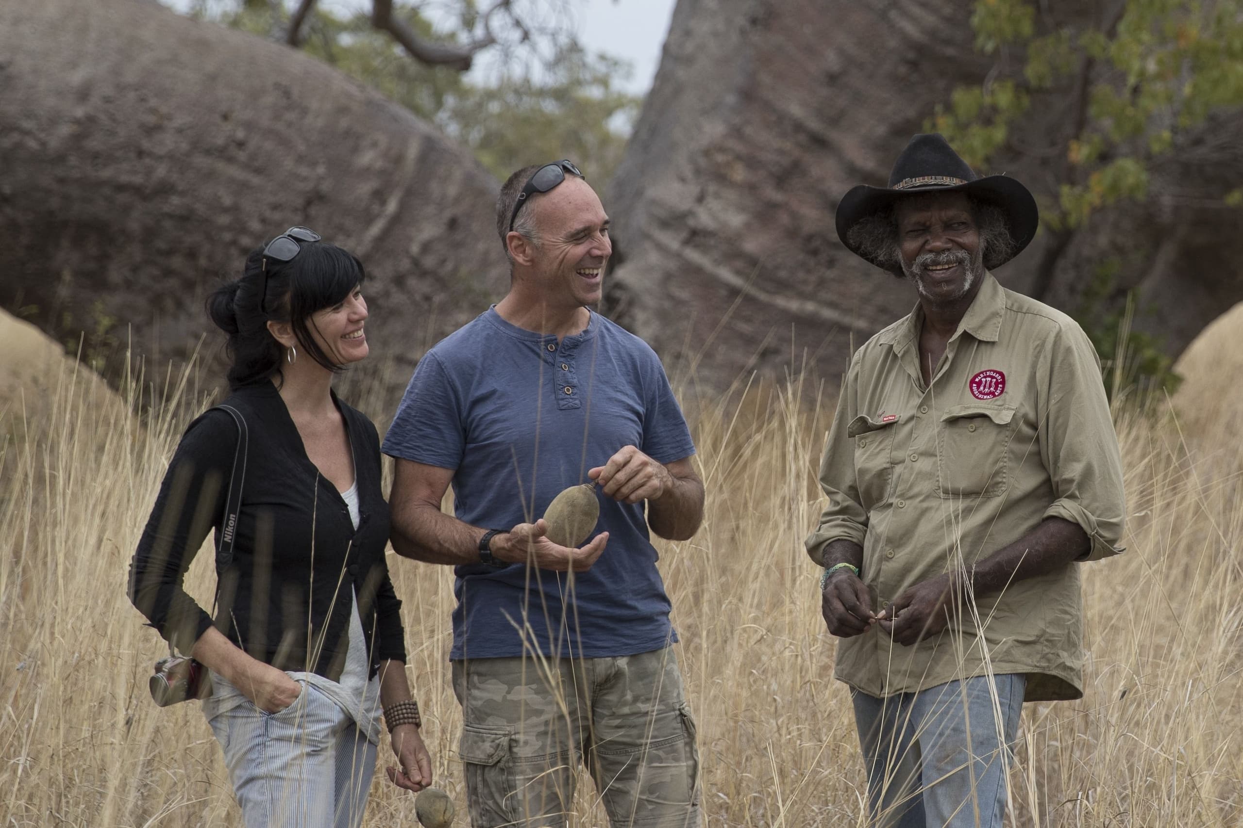 Small guided group walking through tall savanna grasses with Aboriginal guide