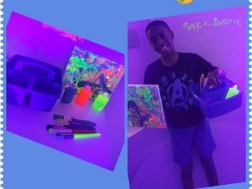 Person holding glow paint supplies in indoor neon paint studio