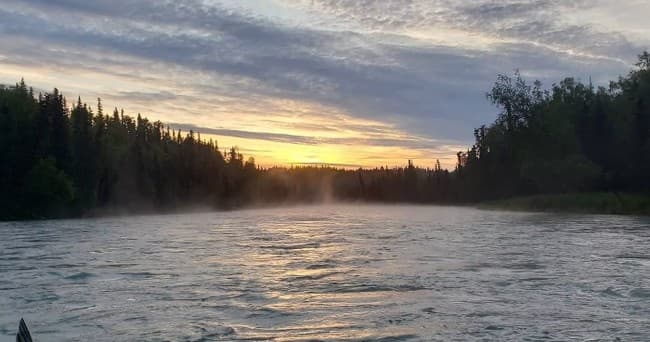 Sunset river view with mist over water and forested treeline