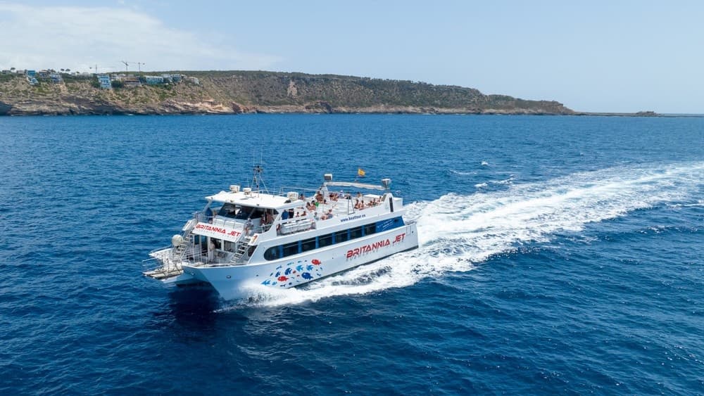 Passenger tour boat speeding across blue open sea with wake