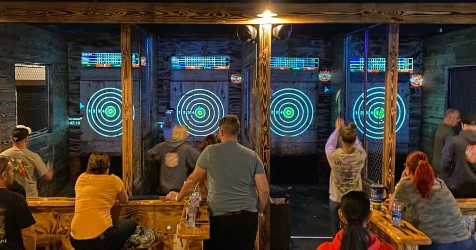 Crowd watching players across multiple indoor axe lanes in Ocala