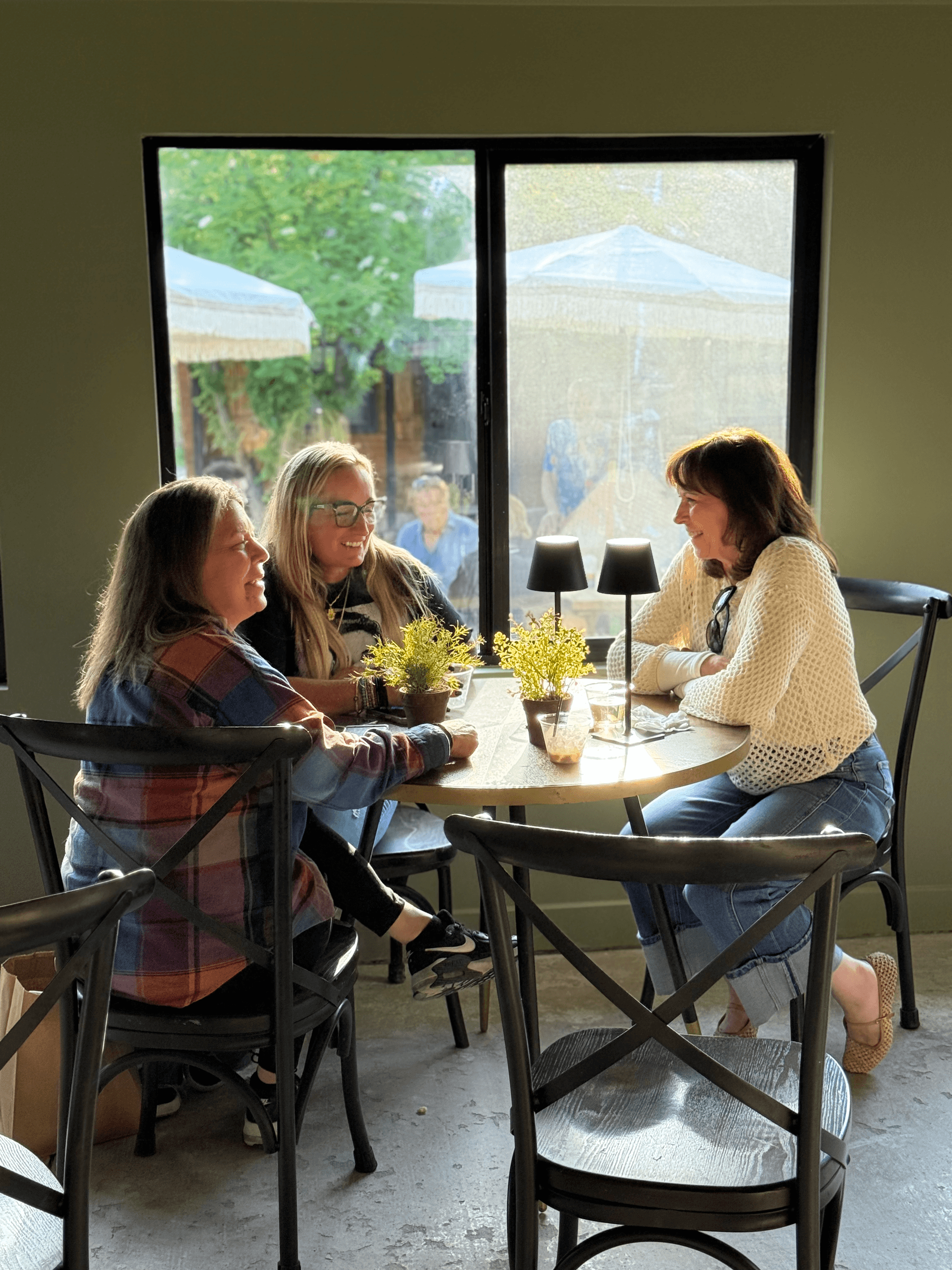 Women chatting at cafe table by window during casual meetup