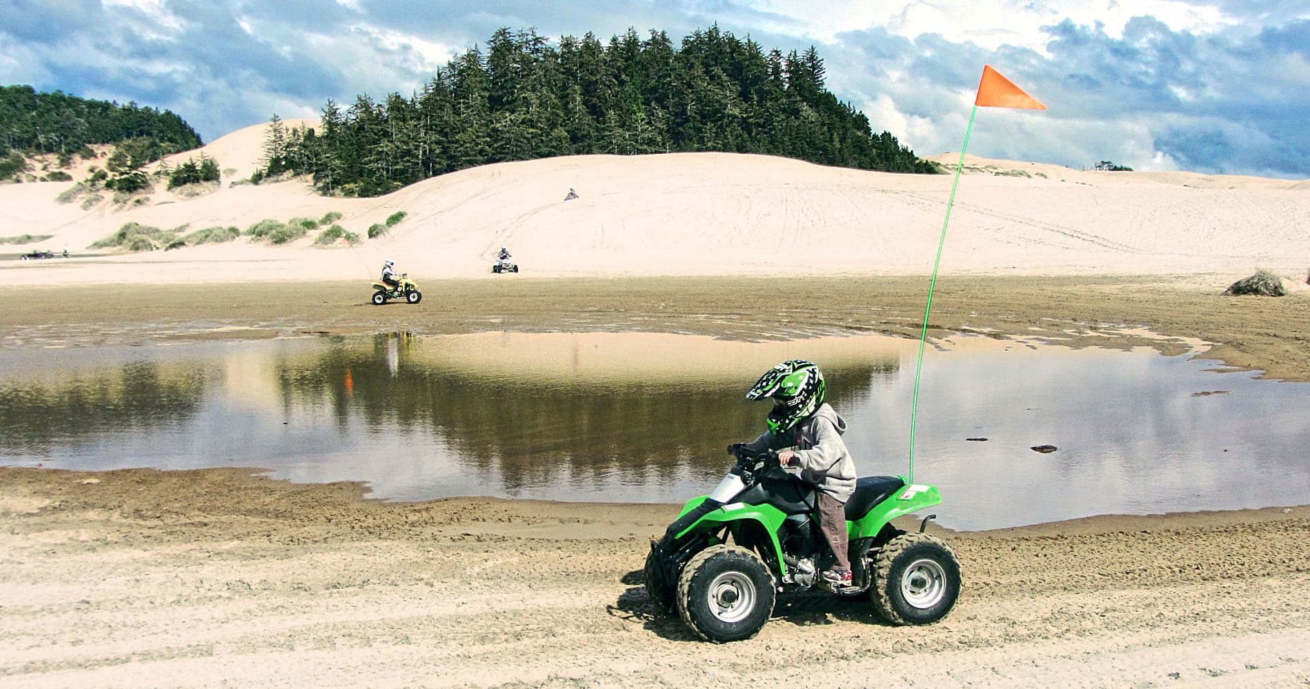Rider on ATV by coastal dunes and lagoon, beach off-road ride