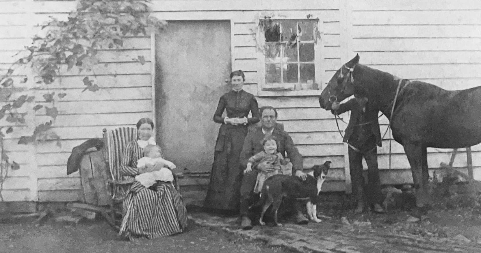 Vintage rural family portrait with horse outside farmhouse