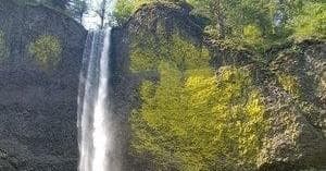Tall waterfall cascading into basalt gorge, scenic waterfall hike