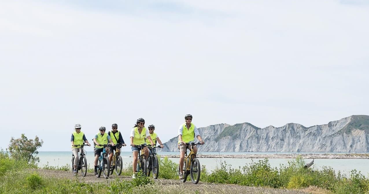 Cyclists riding a coastal path beside cliffs with ocean views