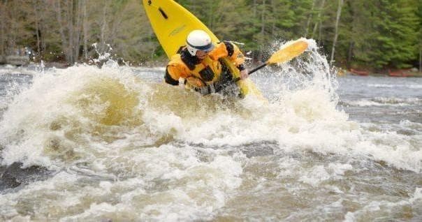 Solo kayaker tackling turbulent whitewater waves on river run