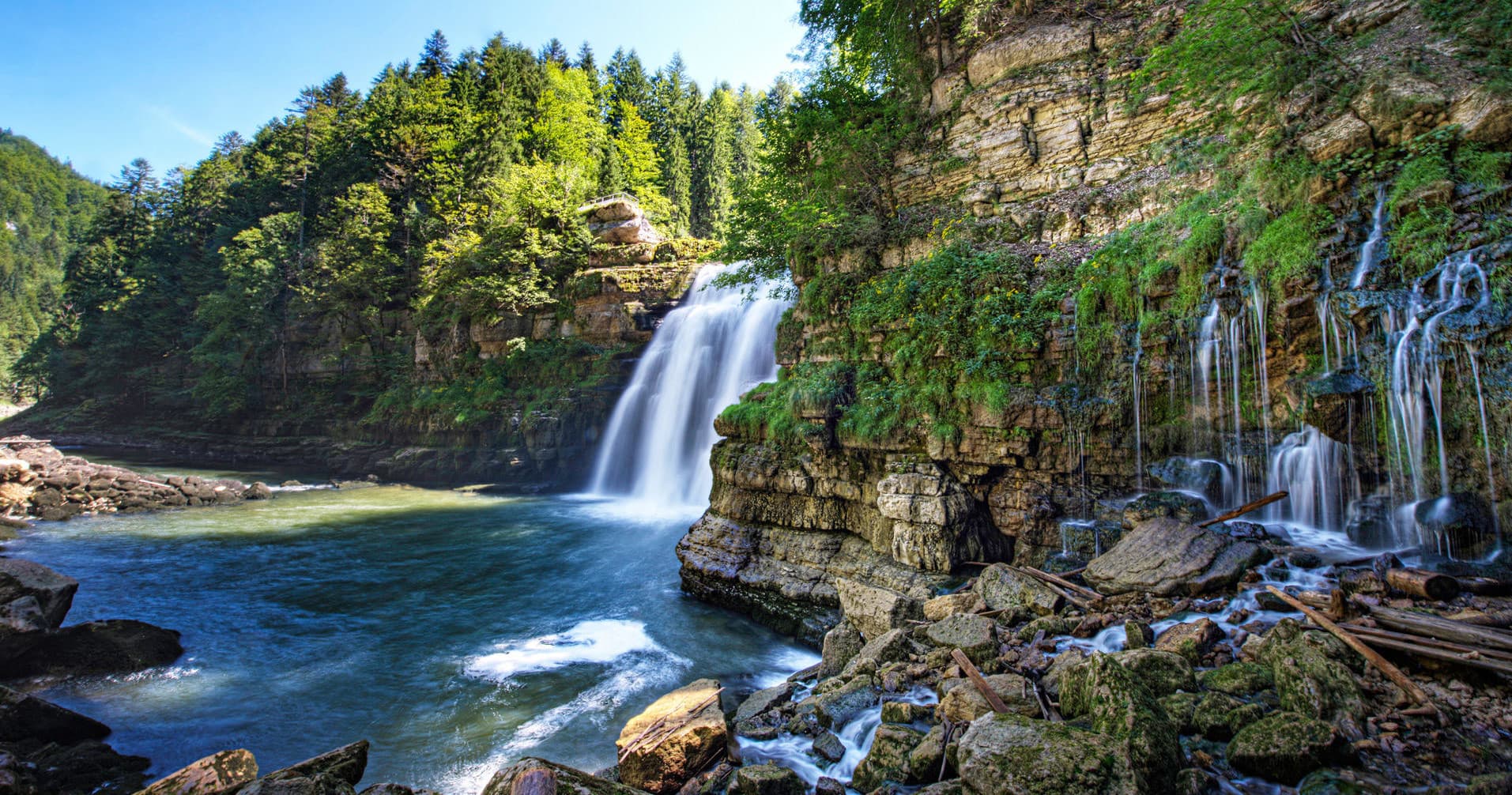 Waterfall and river gorge surrounded by forested cliffs