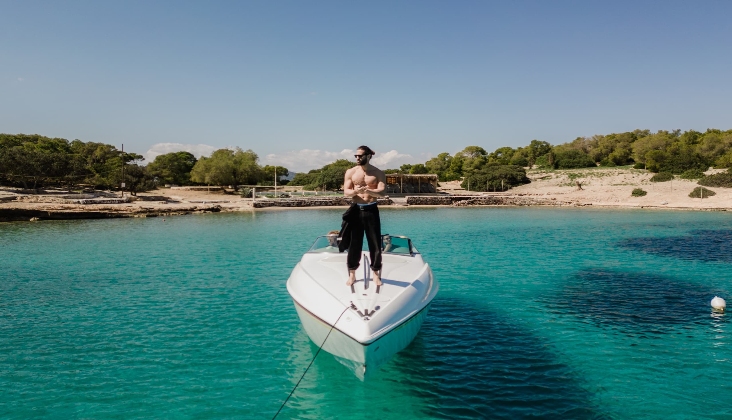 Couple on bow of boat anchored in shallow turquoise bay