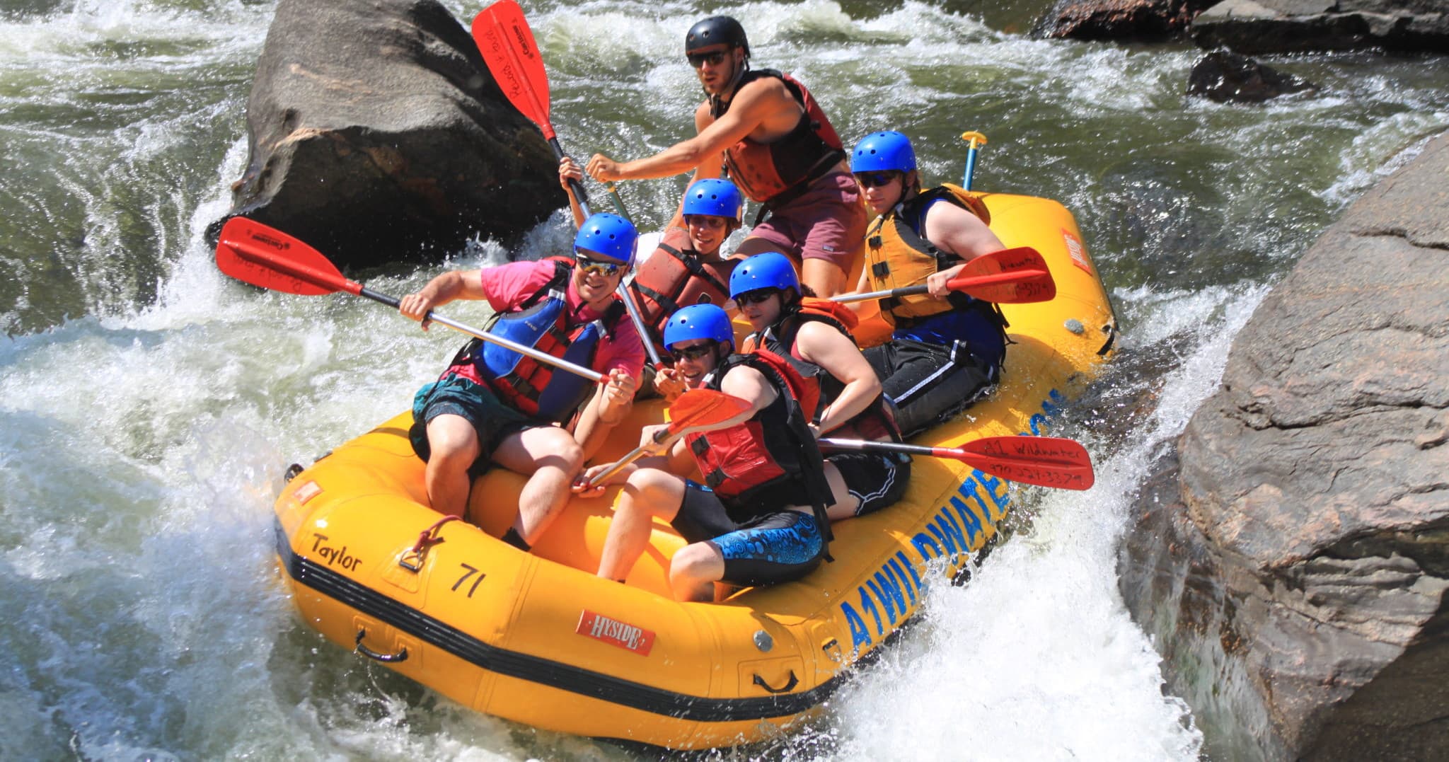 Adventurers paddling a yellow raft through steep whitewater rapids
