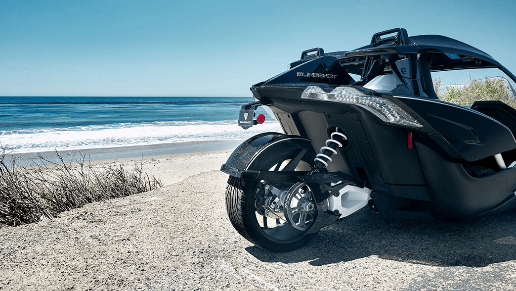 Blue Slingshot convertible by palm-lined beach coastline