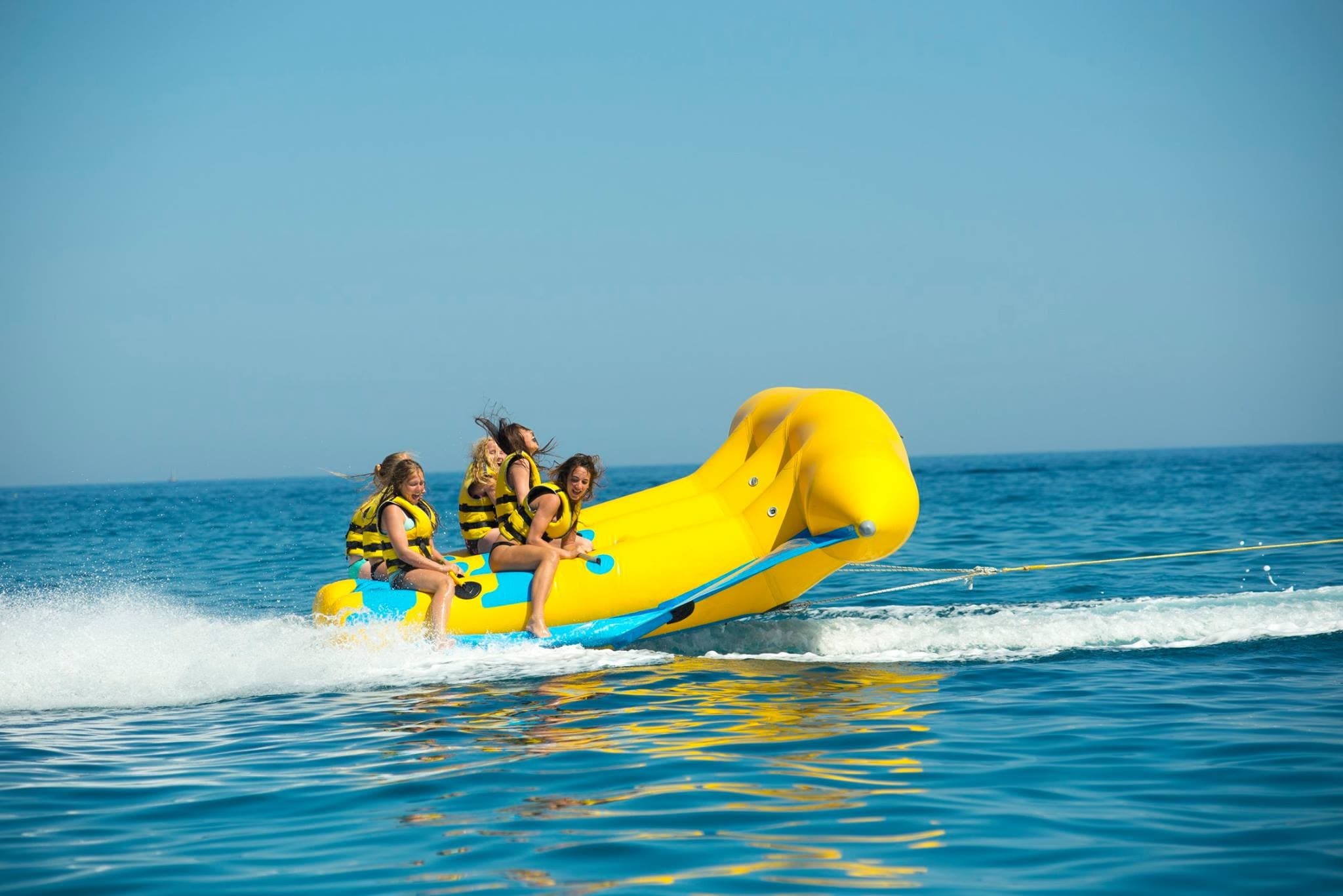 Yellow banana boat riders bouncing on crystal blue Mediterranean water
