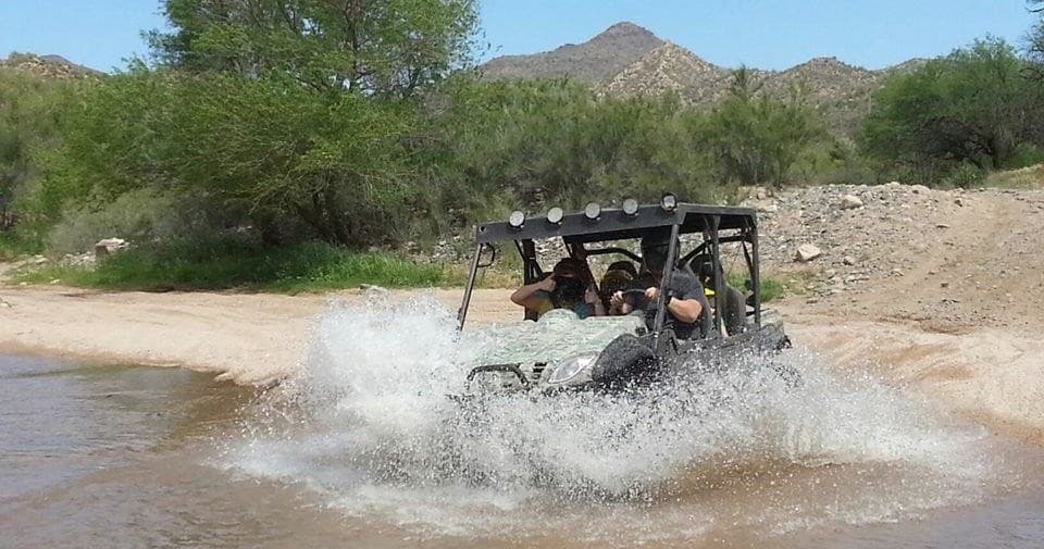 UTV splashing through shallow desert water crossing on tour