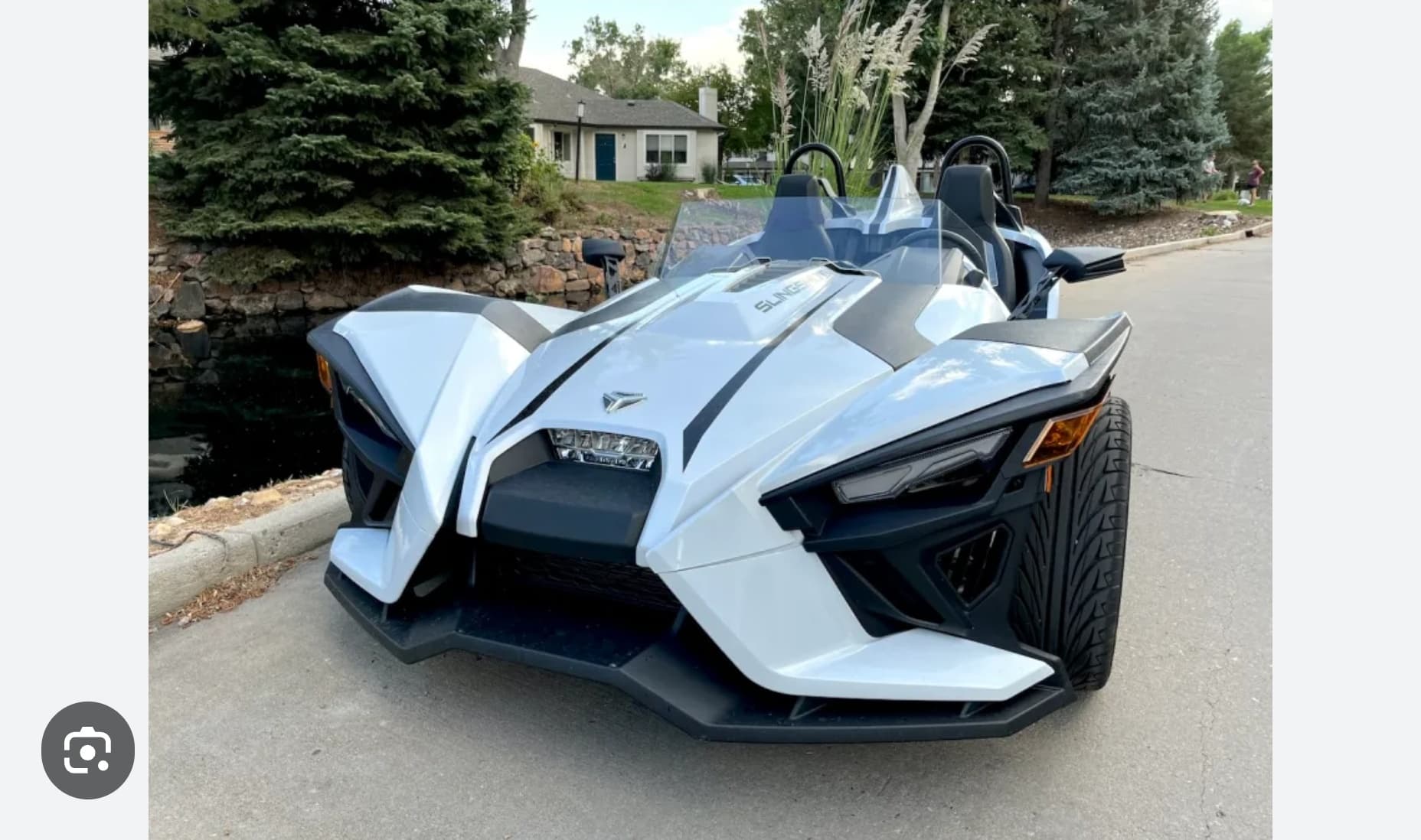 Open-air Slingshot three-wheeler on tree-lined suburban road