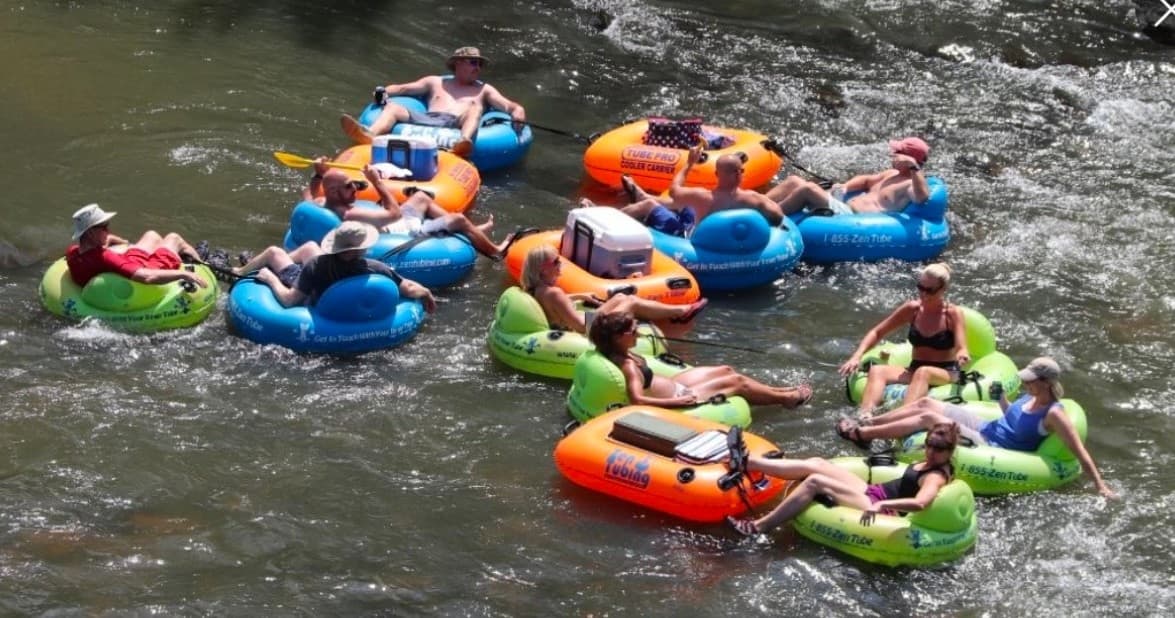 Group river tubers floating down a sunlit rocky river in summer