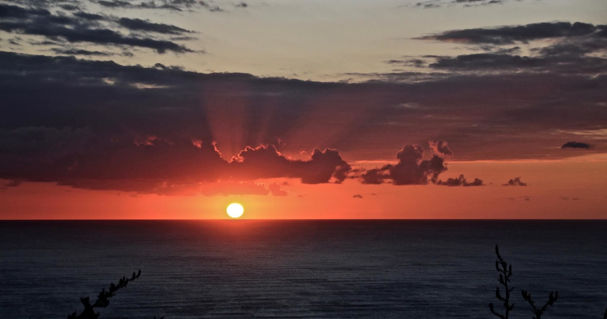 Sunset over Muriwai Beach coastline with dramatic ocean colors