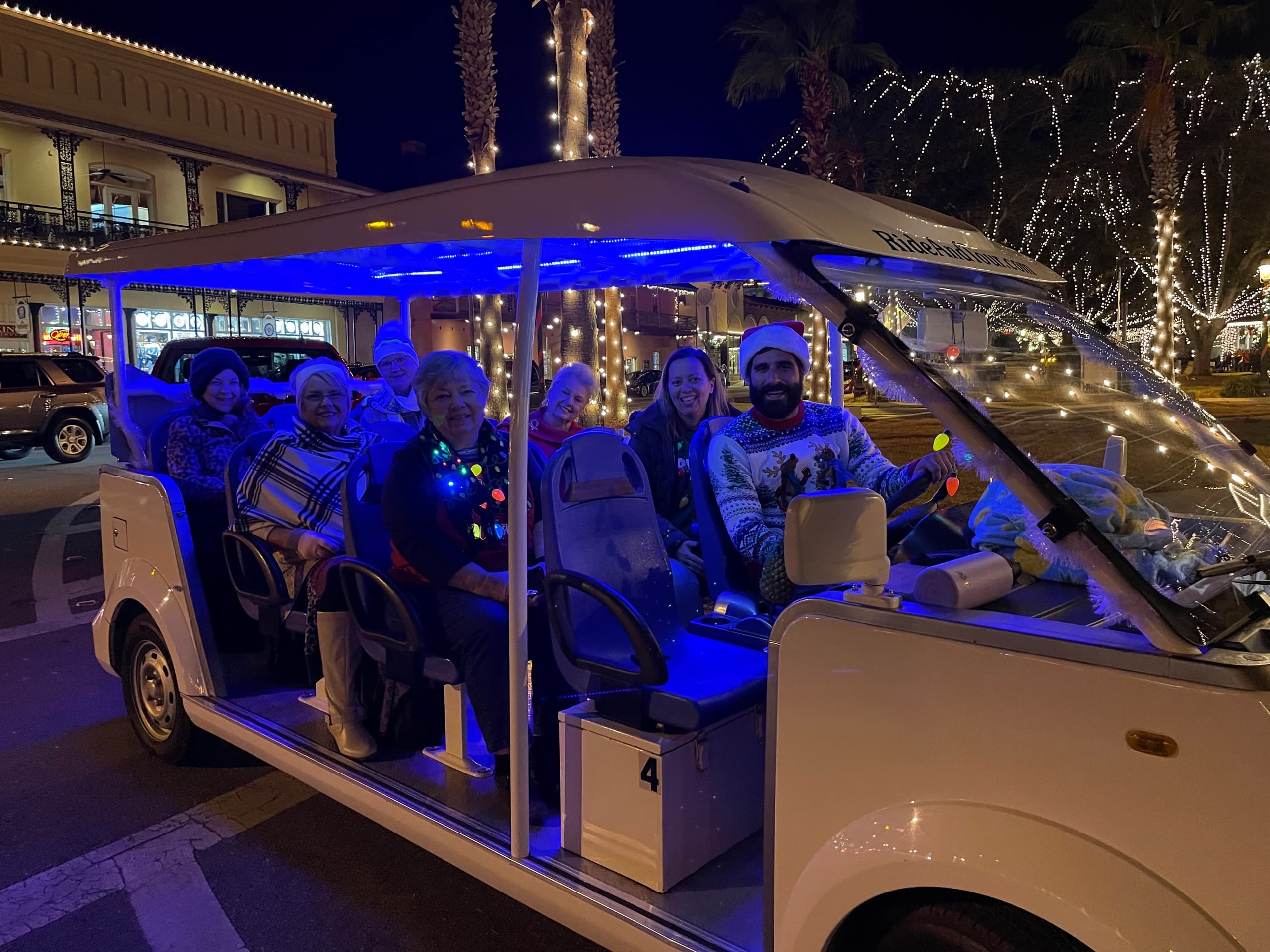Nighttime electric tour tram lit with festive lights and passengers
