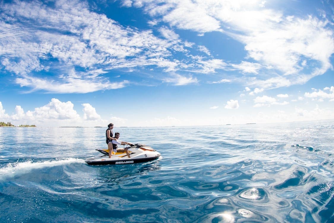 Couple jet skiing on tropical coastal waters under blue sky