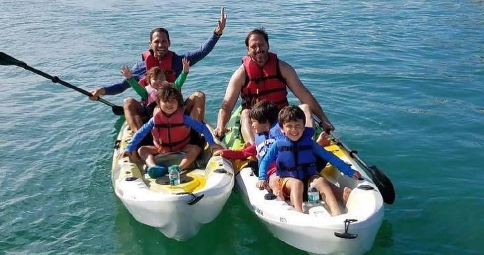 Family kayaking together in clear coastal waters near shore
