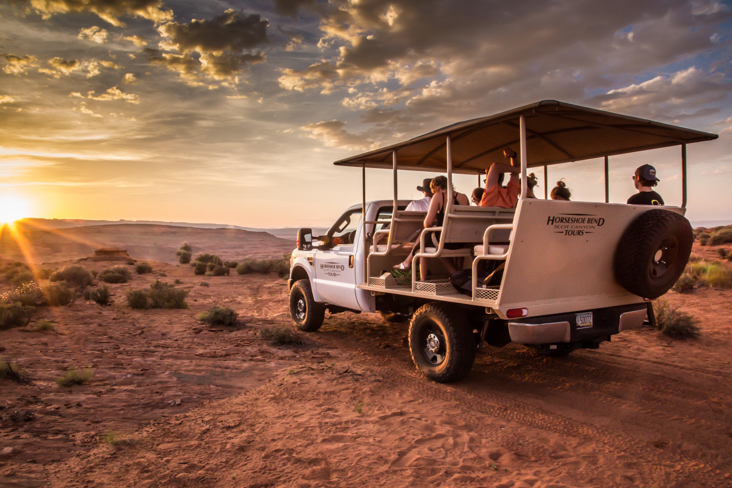 Open-air tour truck at sunset with scenic desert view