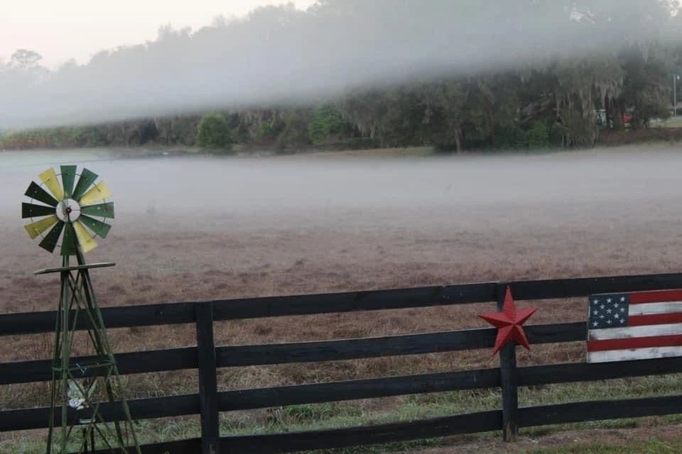 Misty morning farm field with decorative windmill and fence