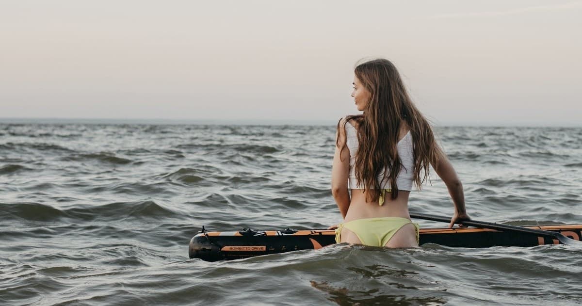 Paddleboarder sitting on board looking out over choppy sea