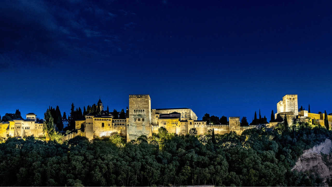 Alhambra fortress illuminated at night over Granada skyline