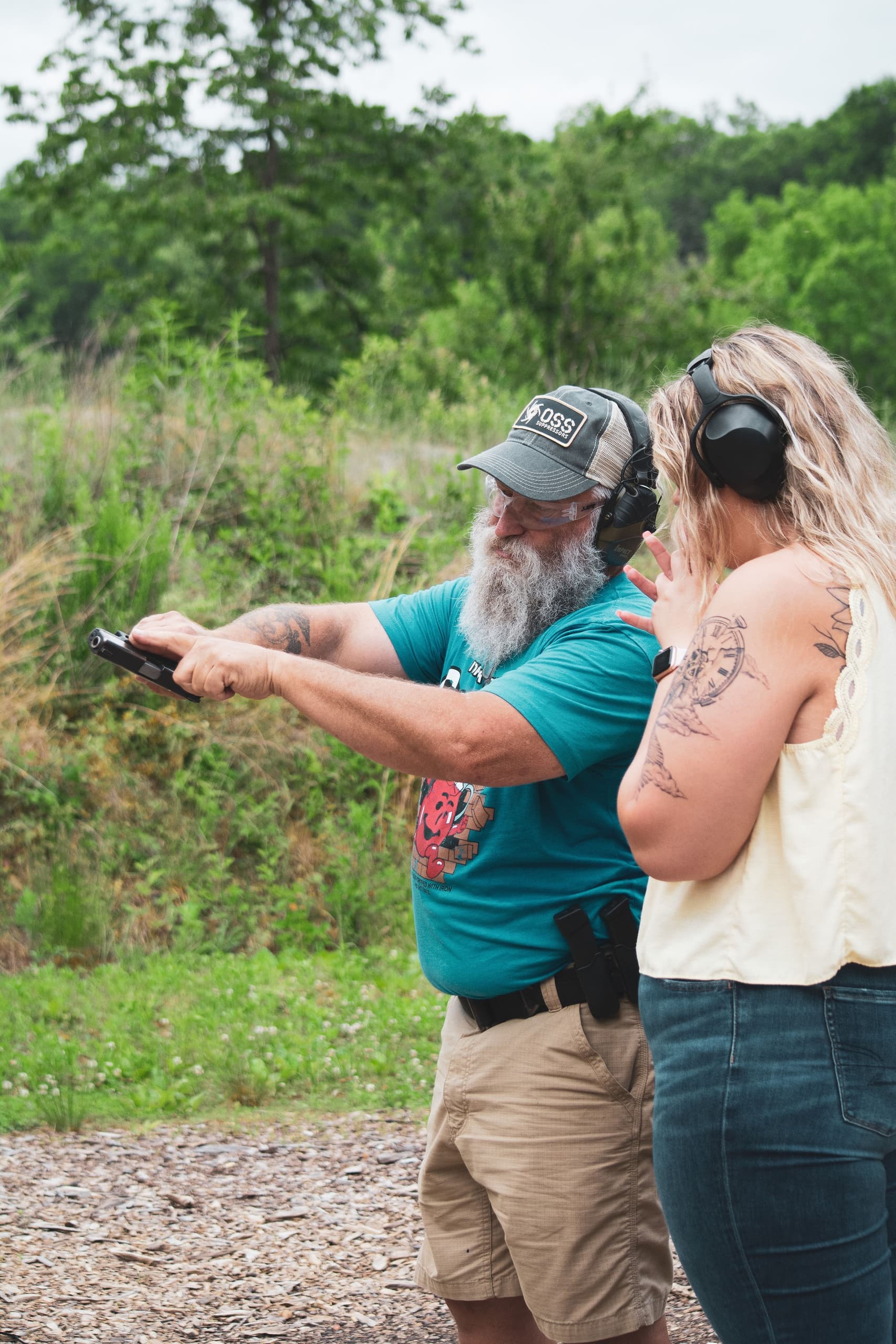 Instructor coaching student pistol shooting on outdoor range