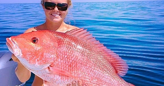 Angler holding large red snapper in open Gulf waters off Destin