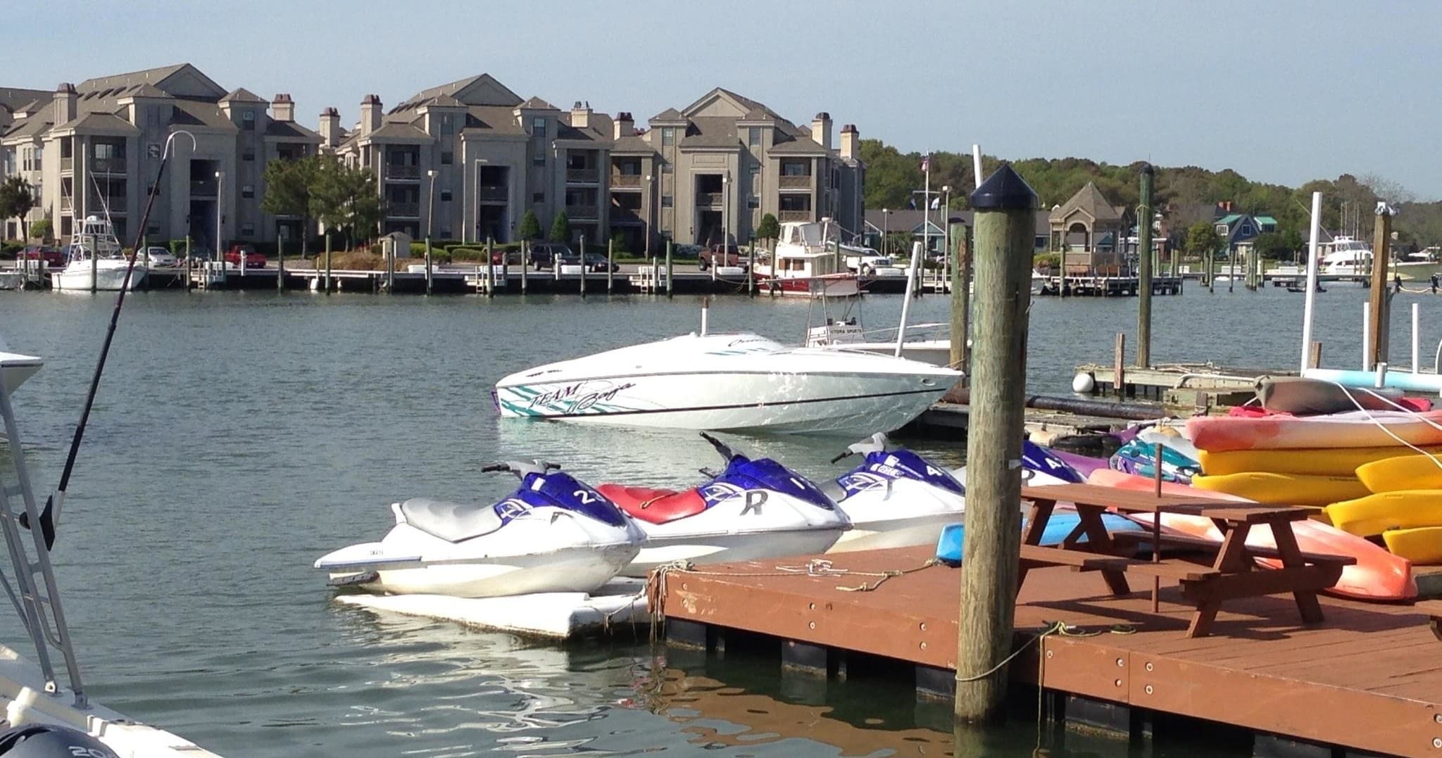 Kayaks and jet skis docked at marina with waterfront homes