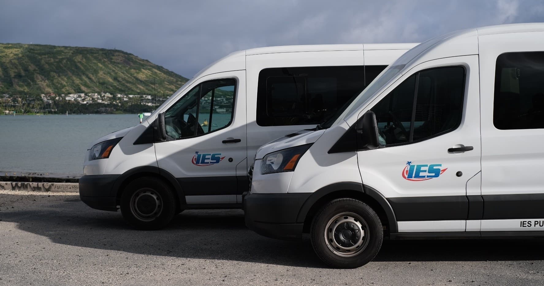 Island Express shuttle vans parked by coastal road with cliffs