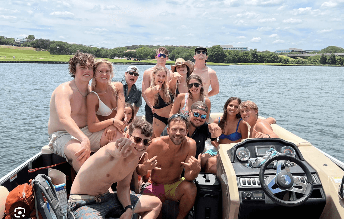 Large group partying on motorboat at sunny lakeside gathering