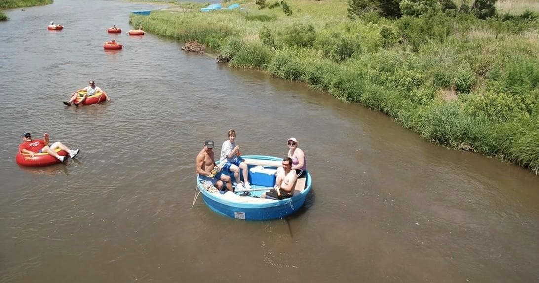 Group floating in blue river tubs on a calm scenic river